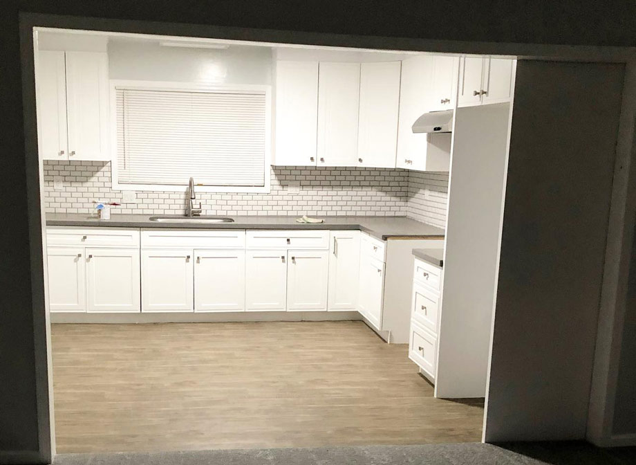white kitchen area with kitchen cabinet, white backsplash, table top