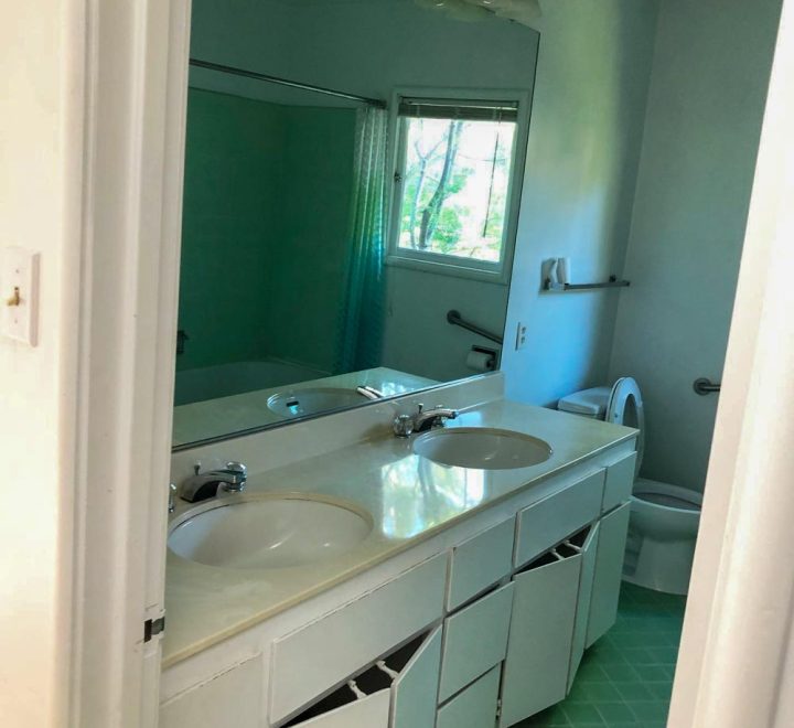 bathroom with double sink, mirror and toilet