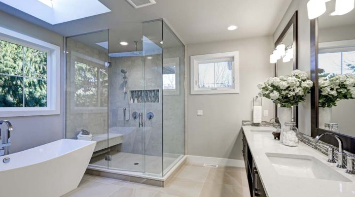 Spacious bathroom in gray tones with heated floors, freestanding tub, walk-in shower, double sink vanity and skylights